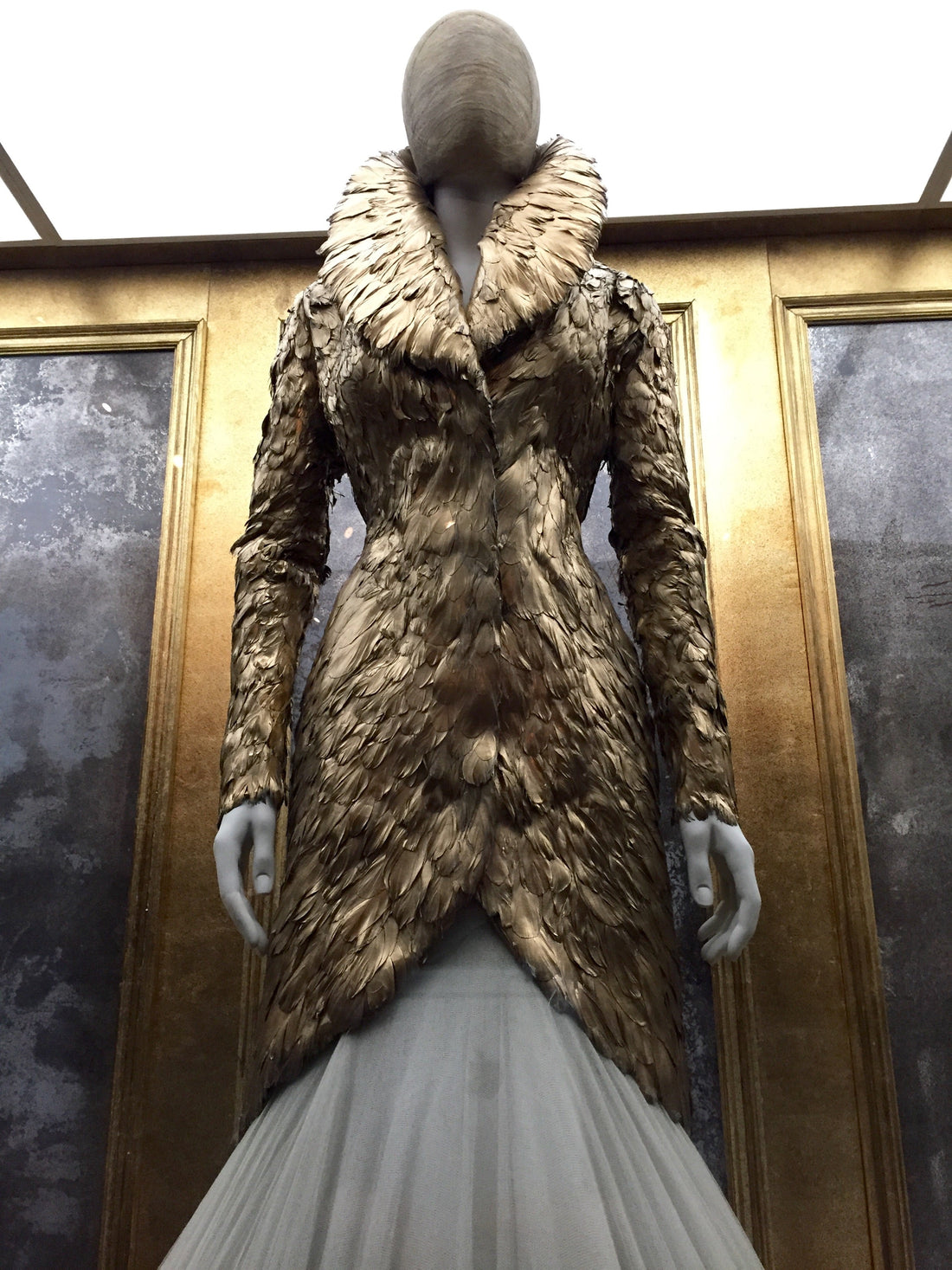 Gold feathered coat from Alexander McQueen’s Angels & Demons collection displayed at the V&A exhibition.