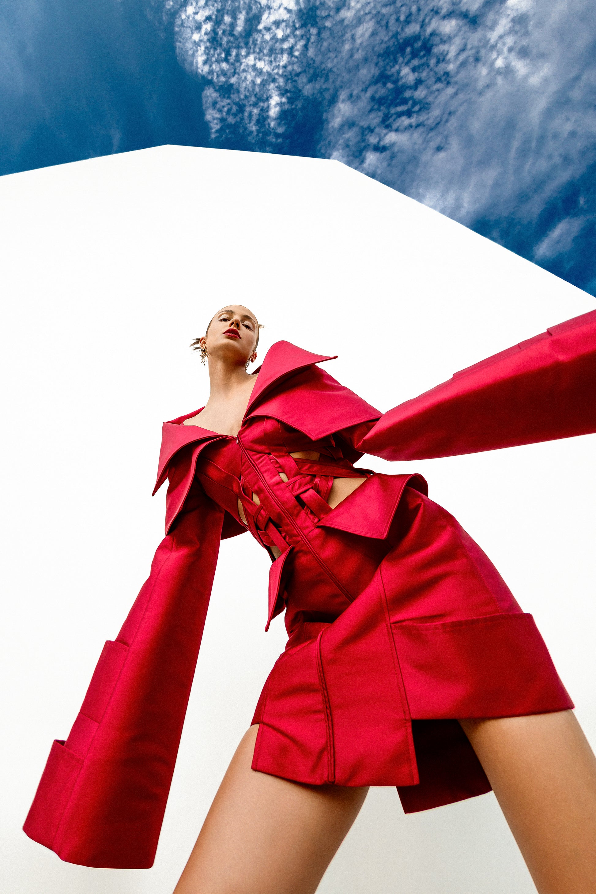 Obsidian Bloom avant-garde editorial outdoor low-angle view featuring sculptural red construction and woven waist cutouts
