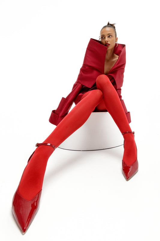 Obsidian Bloom red Mikado editorial dress in wide-angle seated portrait with sculptural high collar and elongated architectural sleeves by FlyandFall