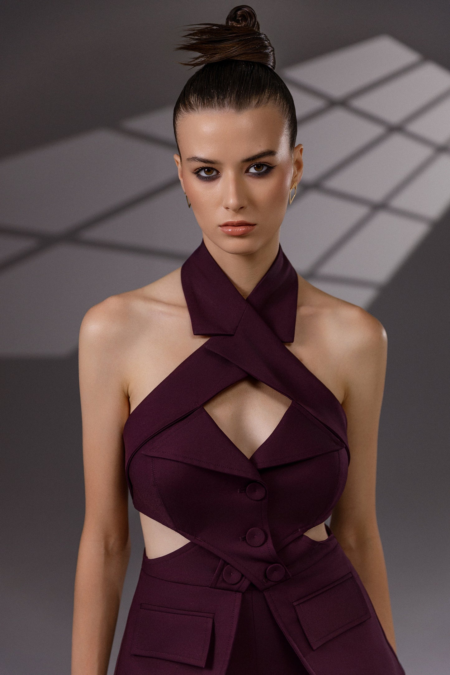 VEYRA Burgundy Crossover Halter Jumpsuit close-up showing the crossover halter neckline, chest cutout, covered buttons and waist cutouts.