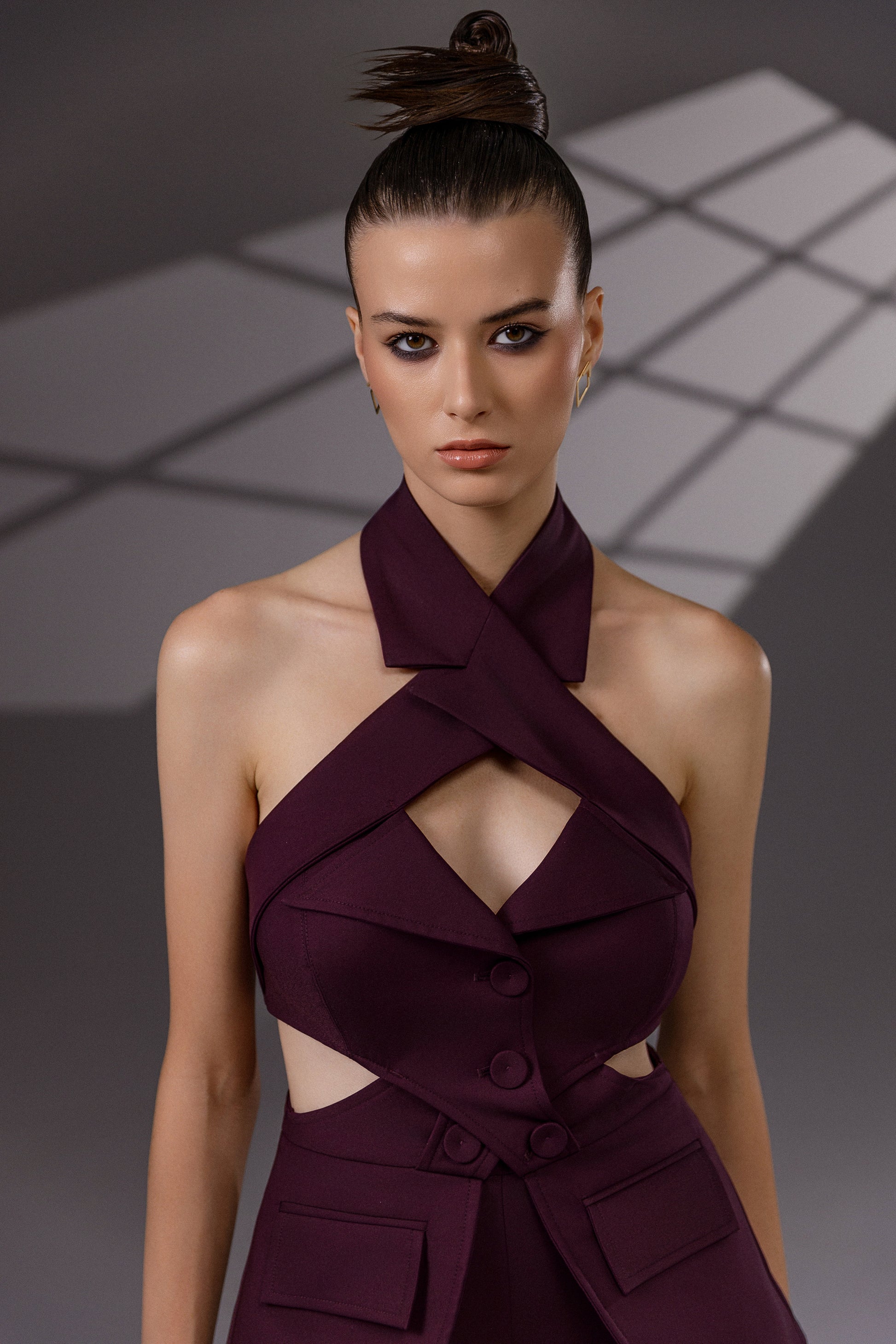VEYRA Burgundy Crossover Halter Jumpsuit close-up showing the crossover halter neckline, chest cutout, covered buttons and waist cutouts.